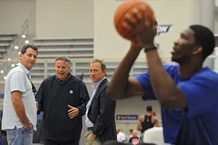 Sixers coach Brett Brown talks with the team's managing partners,  Josh Harris (right) and David Blitzer (left) as they watch  Joel Embiid shoot baskets.