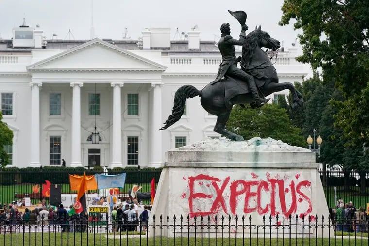 The words "Expect Us" are painted on the base of the equestrian statue of President Andrew Jackson in Lafayette Park as protesters gather to call on the Biden administration to do more to combat climate change and ban fossil fuels outside the White House in Washington, Tuesday, Oct. 12, 2021. The words are part of the phrase "Respect Us, or Expect Us" which indigenous women have been using while protesting oil company Enbridge's Line 3 pipeline through Minnesota.