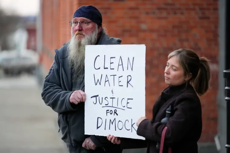 Ray Kemble, left, of Dimock, Pa., and Renee Vogelsang hold a sign outside the Susquehanna County Courthouse in Montrose, Pa., Tuesday, Nov. 29, 2022. Pennsylvania's most active gas driller has pleaded no contest to criminal environmental charges in a landmark pollution case.