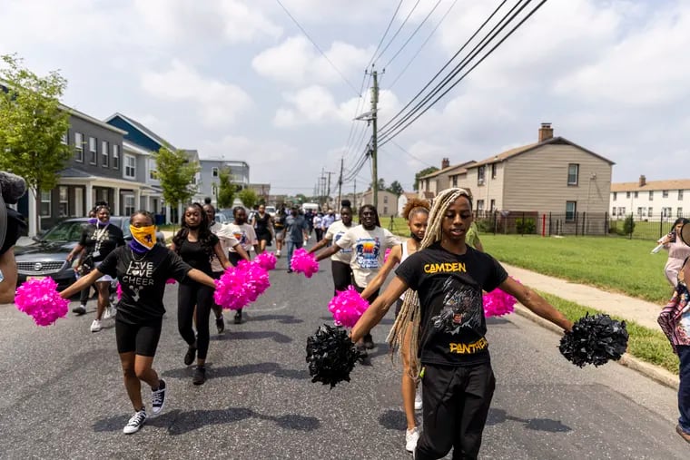 A cheer team follows Camden Mayor Vic Carstarphen as he walks the streets on Tuesday, encouraging the community to get vaccinated.