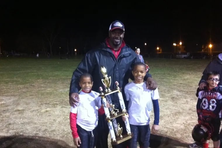 Josiah Trotter (left) poses with his father, Jeremiah Sr. (center), and older brother, Jeremiah Jr. (right), after a youth football game.