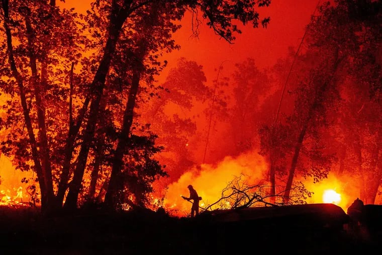 A firefighter douses flames as they push toward homes during the Creek Fire in the Cascadel Woods area of Madera County, Calif., in September. A firework at a gender reveal party triggered a wildfire in Southern California that has destroyed 7,000 acres and forced many residents to flee their homes.