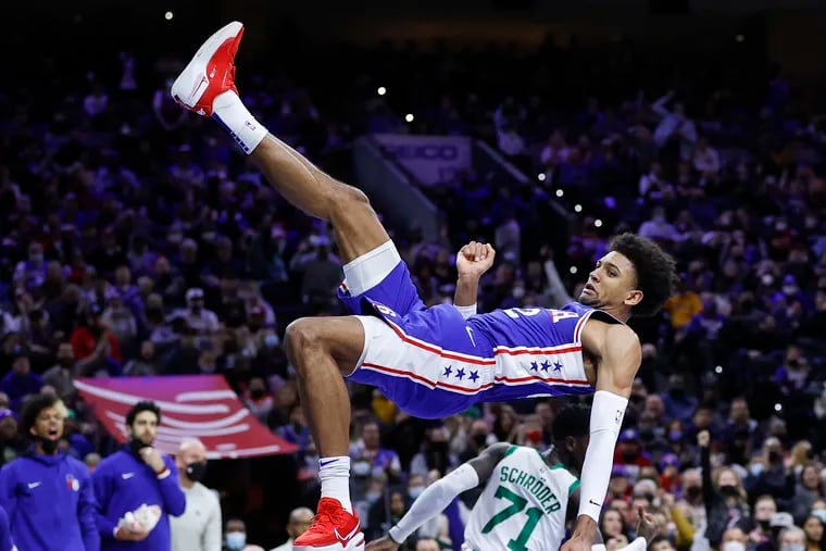 Sixers guard Matisse Thybulle falls down after dunking the basketball after getting fouled by Boston Celtics guard Dennis Schroder in the third quarter on Friday, January 14, 2022 in Philadelphia.