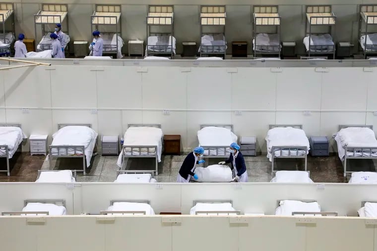 Medical staff prepare beds at a temporary hospital which transformed from an exhibition center for accepting patients who diagnosed with the coronaviruses in Wuhan in central China's Hubei province. Ten more people were sickened with a new virus aboard one of two quarantined cruise ships with some 5,400 passengers and crew aboard, health officials in Japan said Thursday, as China reported 73 more deaths and announced that the first group of patients were expected to start taking a new antiviral drug.