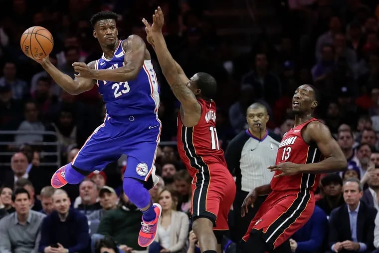 Sixers guard Jimmy Butler leaps in the air with the basketball against Miami Heat guard Dion Waiters and center Bam Adebayo on Thursday, February 21, 2019 in Philadelphia.
