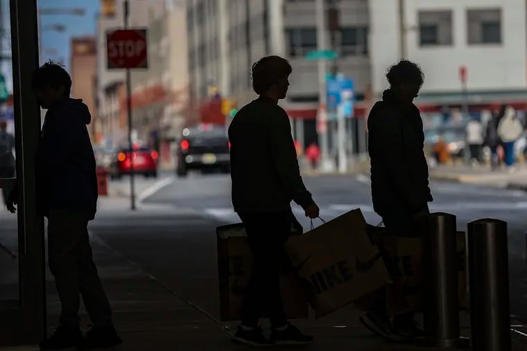 Shoppers are silhouetted as they carry bags exiting the Fashion District by Ninth and Filbert Streets in Philadelphia on Black Friday 2023. Nationwide, buy-now, pay-later services fueled record post-Thanksgiving spending.