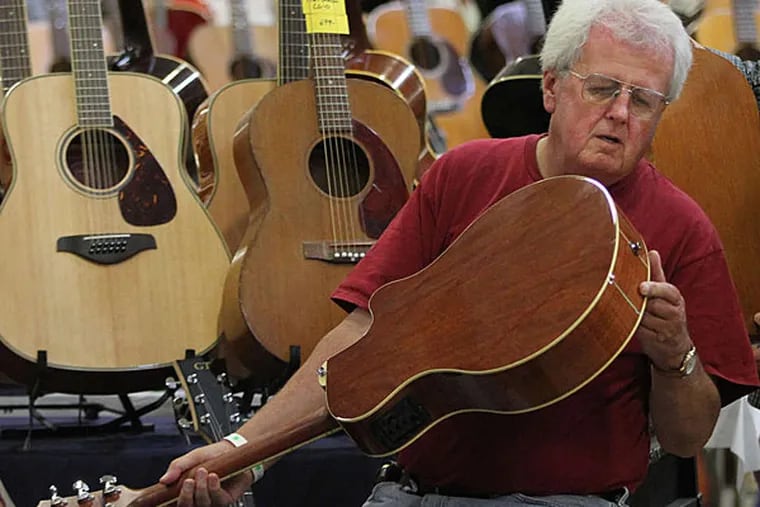 Michael Halloran looks over a Yamaha acoustic at the Great American Guitar Show in Oaks on Sunday. (Michael Bryant/Staff)