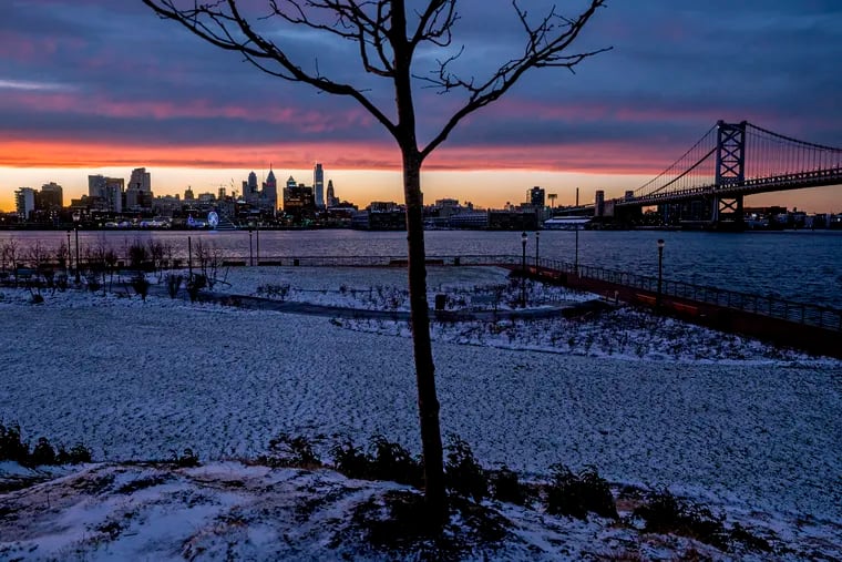 The sun sets behind the Philadelphia skyline and the Ben Franklin Bridge with snow on the ground this week on Camden’s Delaware River Waterfront.
