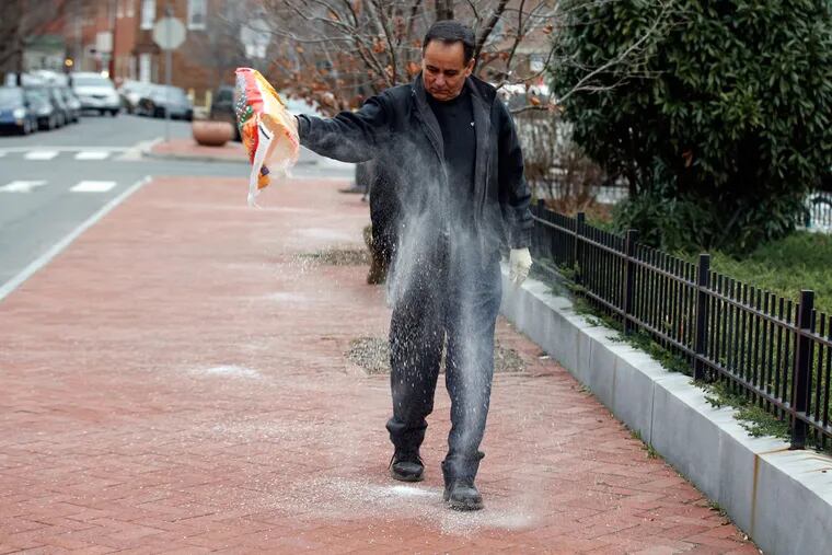 Peter Cundo, owner of Superior Auto Care in Queen Village, salts the sidewalk before snowfall on Friday, Jan. 22, 2016.