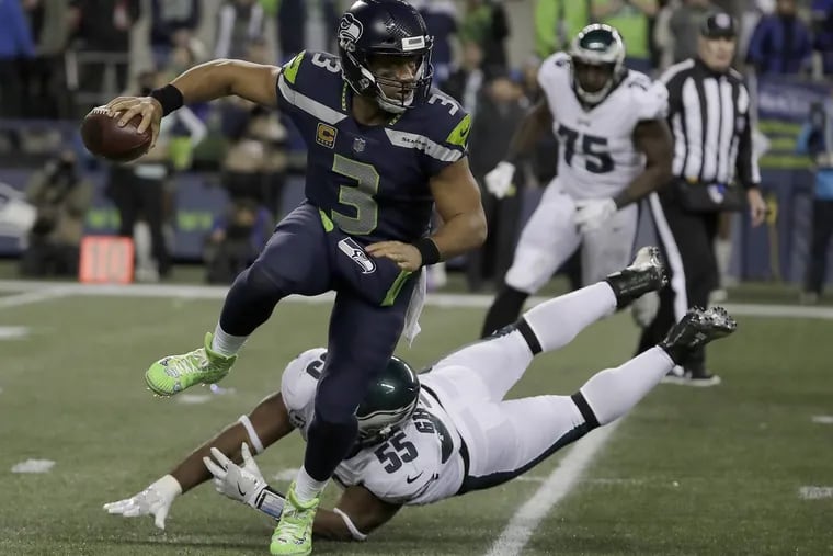 Seahawks’ Russell Wilson, left, scrambles away from the Eagles’ Brandon Graham in the third quarter.
