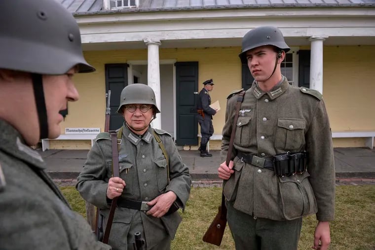 Reenactors Chris Johnson, left, Reter Mahler, center, and Greg Fliescher, dressed as German soldiers, talk about their uniforms during a reenactment of a WWII German POW camp at Fort Mifflin on March 25, 2017. Charles Mostoller / For the Inquirer