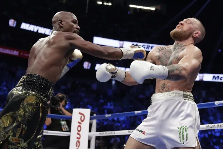 Floyd Mayweather Jr. hits Conor McGregor in a super welterweight boxing match Saturday in Las Vegas.