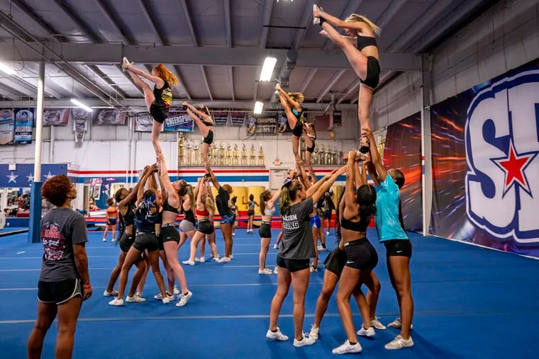 Cheer coach Ashley Martin (left) watches students work on safe cheerleading at the NJ Spirit Explosion gym in Cinnaminson.