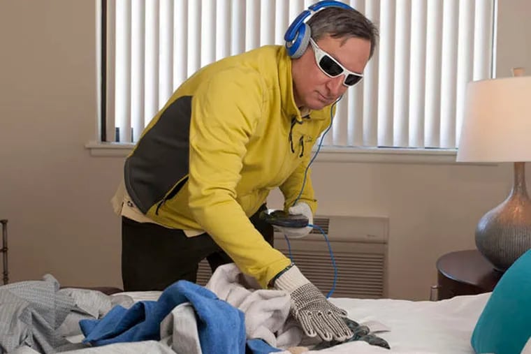 Richard Abraham, whose mother lives at the Watermark, attempts routine household chores with thick gloves, blinding glasses, and disorienting noise.