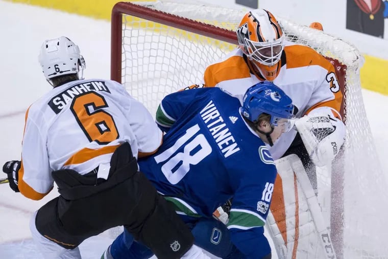 Flyers defenseman Travis Sanheim (6) tries to clear  Canucks right winger Jake Virtanen (18) from in front of goalie Brian Elliott during the second period Thursday.