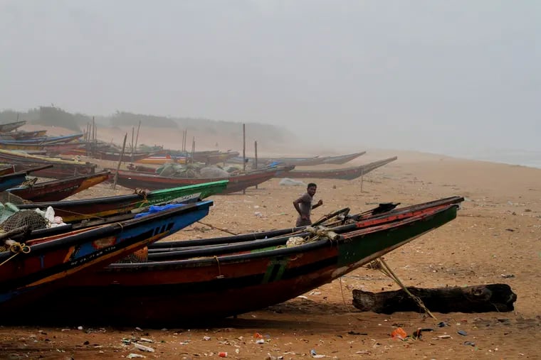 An Indian fisherman runs between the docked fishing boats amid strong winds at Chandrabhaga beach in Puri district of eastern Odisha state, India, Thursday, May 2, 2019. Hundreds of thousands of people were evacuated along India's eastern coast on Thursday as authorities braced for a cyclone moving through the Bay of Bengal that was forecast to bring extremely severe wind and rain.