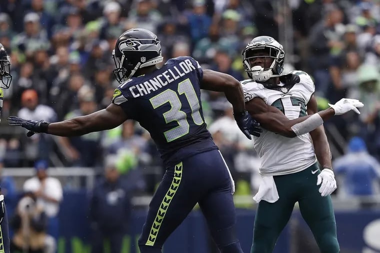 Eagles’ Nelson Agholor (right) takes a swipe at Seahawks' Kam Chancellor.
