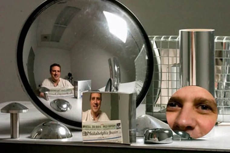 Andrew Hicks, reflected in and among mirrors he has designed. The one in the middle - with the Inquirer print readable - is a non-reversing mirror. (Clem Murray / Staff Photographer)