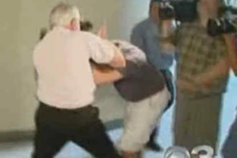 William Siner (left), father of Bonnie Sweeten, attacks a cameraman waiting outside the courtroom.