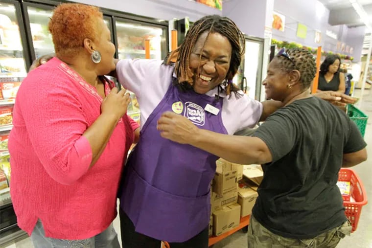 Fare & Square employee Sonia Rollins (center) hugs friends who were shopping at Saturday's grand opening.