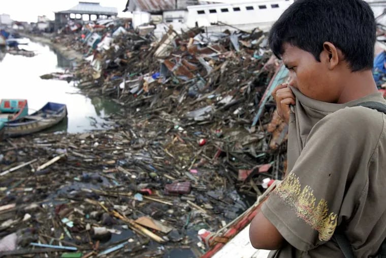FILE - In this Saturday Jan. 1, 2005 file photo, a man looks at a floating debris and dead bodies on Aceh River in Banda Aceh, Indonesia. The tsunami that struck on Dec. 26, 2004, was one of the worldâ€™s worst natural disasters in modern times. The tsunami that struck on Dec. 26, 2004, was one of the worldâ€™s worst natural disasters in modern times. It followed a magnitude 9.1 earthquake that ruptured the sea floor off Indonesiaâ€™s Sumatra island, displacing billions of tons of water and sending waves 10 meters (33 feet) high radiating across the Indian Ocean at jetliner speeds. Associated Press journalists who covered the story recall some of the most poignant images from the disaster. (AP Photo/Eugene Hoshiko, File)