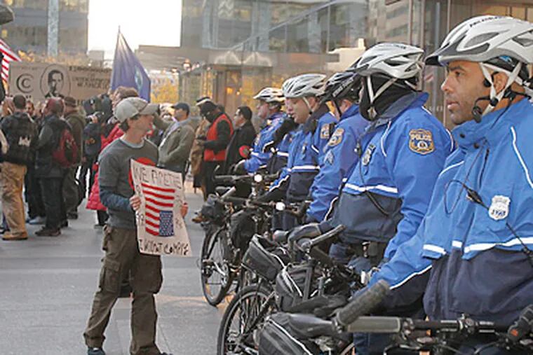 Bike police officers at the Comcast Center watched demonstrators as they protested the company’s tax breaks and the pay of Comcast’s CEO. (Akira Suwa / Staff Photographer)