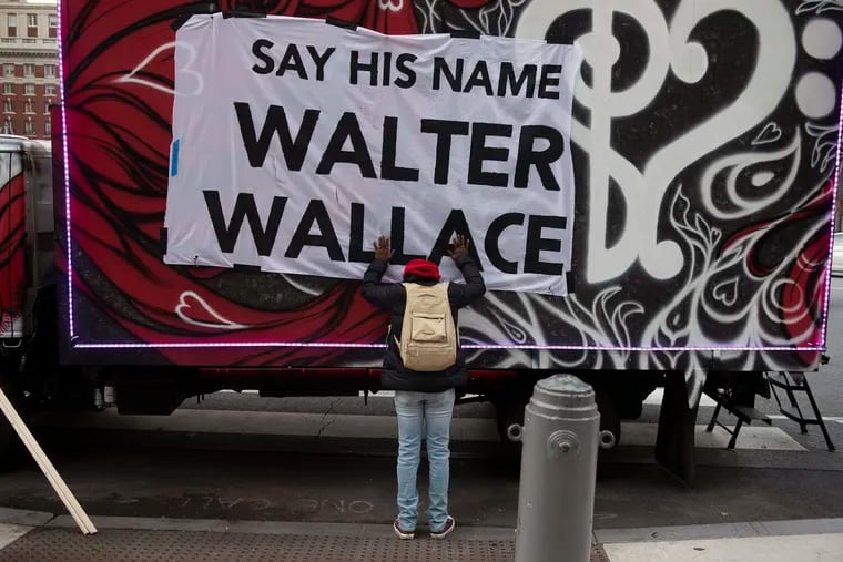 In this Nov. 4, 2020, photo, Sheila Rhames rests her hands on a banner honoring Walter Wallace Jr. in Philadelphia. Wallace, a Black man, was shot and killed by police in West Philadelphia in October 2020. Rhames was his neighbor.