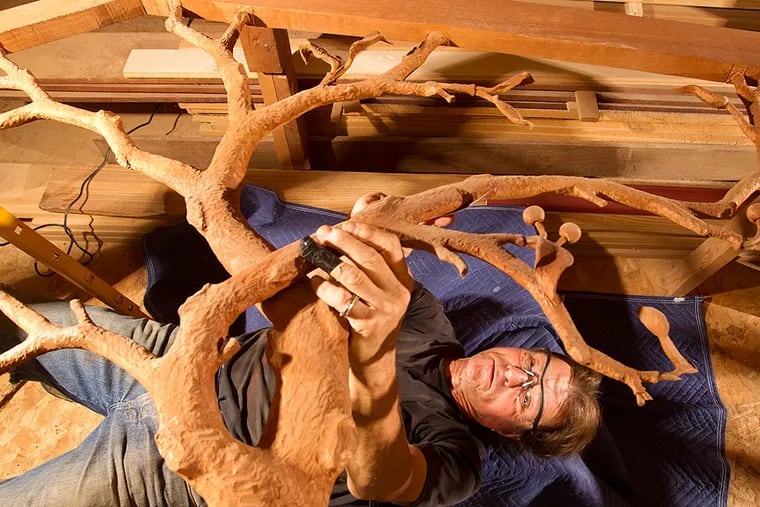 Sculptor Frank Seder Jr. lies on his back while he works in his Deptford studio. Seder, who is carving a staff for Pope Francis, previously created gifts for Pope Benedict XVI and Pope John Paul II. CHARLES FOX / Staff Photographer