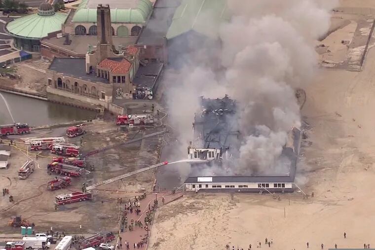 In this screen grab from Chopper 12 video provided by News 12 New Jersey, firefighters battle a blaze at the Dunes Boardwalk Cafe, Saturday, April 13, 2019, in Ocean Grove, N.J. (News 12 New Jersey via AP)
