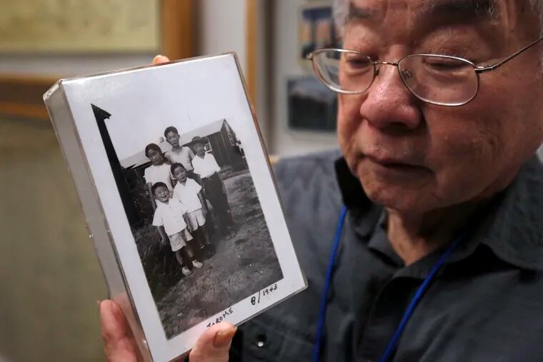 Les Ouchida holds a 1943 photo of himself (front row, center) and his siblings taken at the internment camp his family was moved to in 1942.