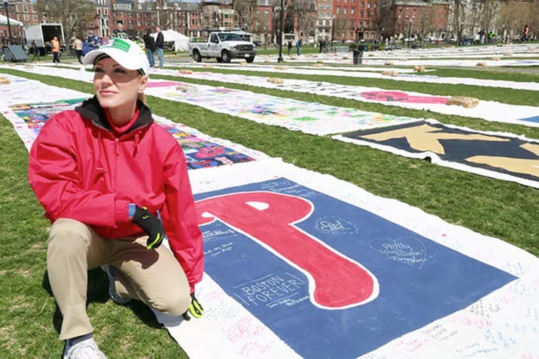 Kari Wagner, founder of America 4 Boston, kneels near a prayer canvas from Philadelphia, one of more than 200 sentby well-wishers from all over the country and unfurled on Boston Common. DAVID SWANSON / Staff Photographer