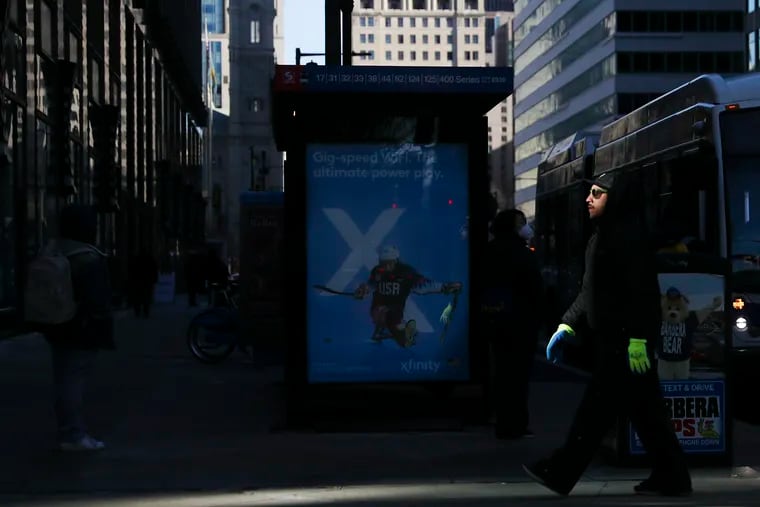 A pedestrian dressed for the cold weather walks past an avertisement for the Winter Olympics near 17th and JFK Blvd. in Philadelphia on Wednesday, Jan. 26, 2022. A winter weather storm is expected later this week.