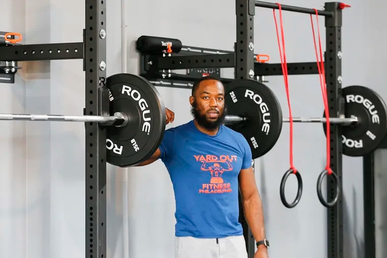 Ron Johnson stands next to weights inside his Yard Out Fit Club Philadelphia in Germantown. After coming out of federal prison in 2018, Johnson set out to use the fitness skills he learned while locked up to create a new life for himself.