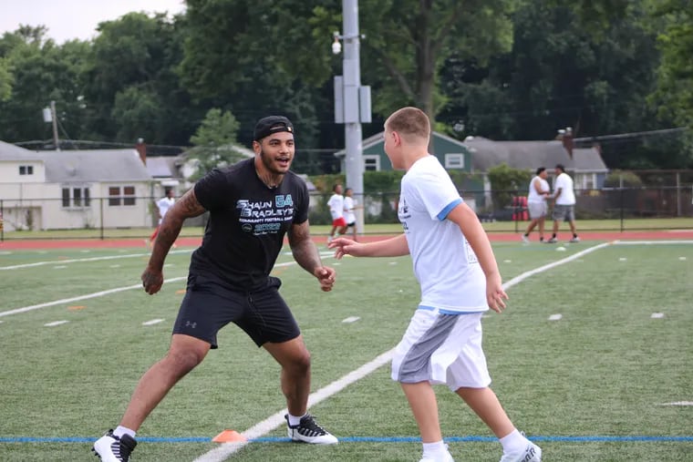 Eagles linebacker Shaun Bradley works out with a player during his football camp at Rancocas Valley Regional High School.