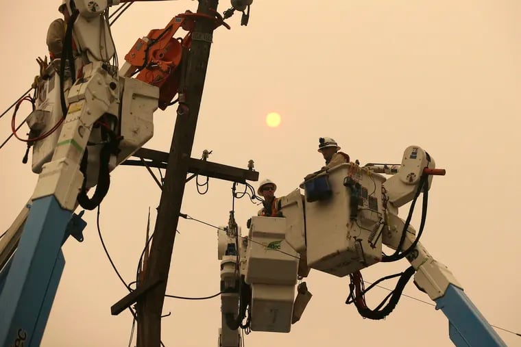 In this Nov. 9, 2018 file photo, Pacific Gas & Electric crews work to restore power lines in Paradise, Calif. Pacific Gas and Electric says it has reached a $13.5 billion settlement that will resolve all major claims related to devastating wildfires blamed on its outdated equipment and negligence. The settlement, which the utility says was reached Friday, Dec. 6, 2019, still requires court approval.