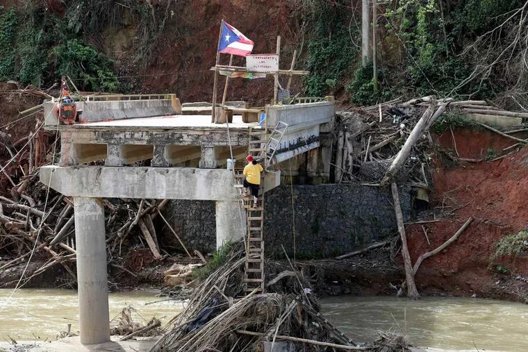 A man climbs up the remains of the only bridge over the Arecibo River connecting Río Abajo to the Puerto Rican town of Utuado Thursday, November 2, 2017.