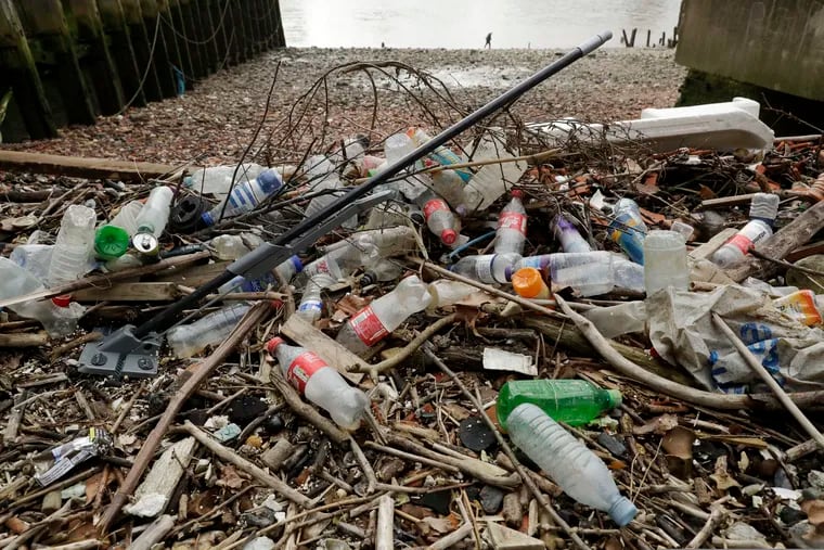 FILE - In this Feb. 5, 2018 file photo, plastic bottles and other plastics including a mop, lie washed up on the north bank of the River Thames in London. European Union officials agreed on Wednesday, Dec. 19, 2018, to ban some single-use plastics, such as disposable cutlery, plates and straws, in an effort to cut marine pollution. The measure will also affect plastic cotton buds, drink stirrers, balloon sticks, and single-use plastic and polystyrene food and beverage containers. (AP Photo/Matt Dunham, File)