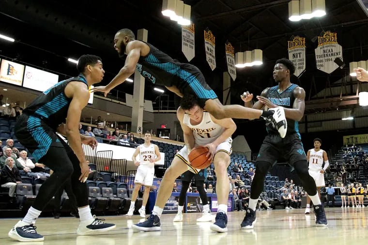 Jeantal Cylla, top center, of UNC Wilmington goes flying over James Butler of Drexel after being faked off the court in the 2nd half on Feb. 7, 2019.