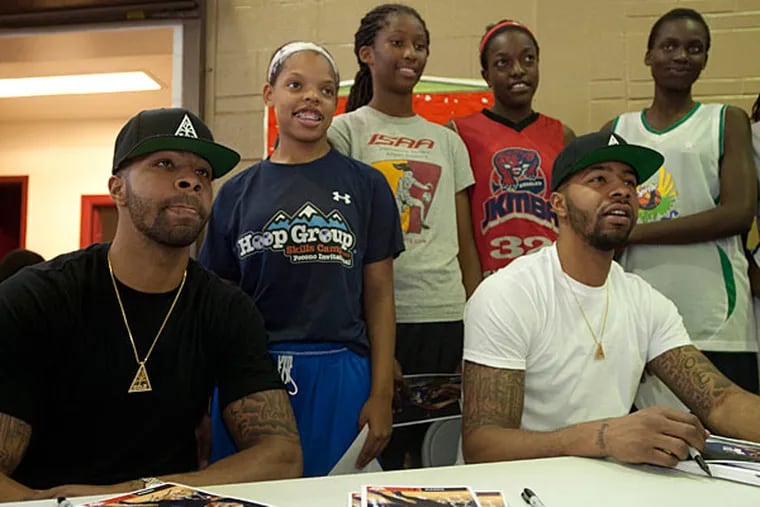 Marcus (left) and Markieff Morris take a break from signing autographs
to pose for a photo at a charity event in the Hunting Park Rec Center
in North Philadelphia. (Ron Tarver/Staff Photographer)