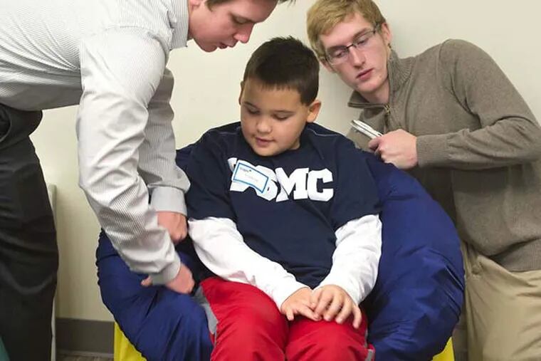 n an engineering class at the Center for Advanced Professional Studies (CAPS) in the Blue Valley School District, students Austin Edmondson, 17, left, and Zach Naatz, 18, right, both seniors, adjust a sensory chair for Jackson Finkeldei, 9, who suffers from Sensory Processing Disorder. The students, seven in all, have designed this sensory chair and sensory recliner in hopes of helping children with autism. The chairs are also called "Snuggle Chairs" because the chair adjusts to snuggle the child, which has a calming effect. (Tammy Ljungblad/Kansas City Star/TNS)
