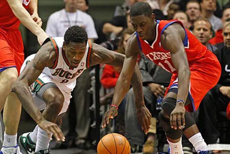 Sixers point guard Jrue Holiday and the Bucks' Larry Sanders chase after the ball in the first half. (AP Photo)