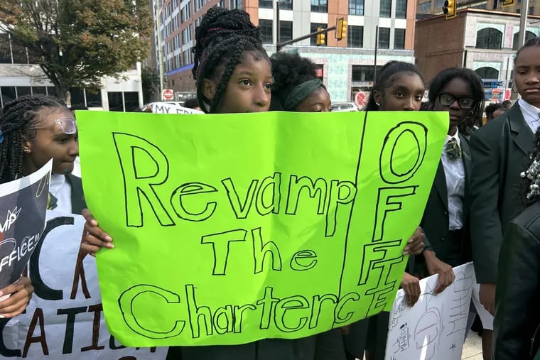 A student holds a sign urging the Philadelphia school board to "Revamp The Charter Office" at a rally before a school board meeting.