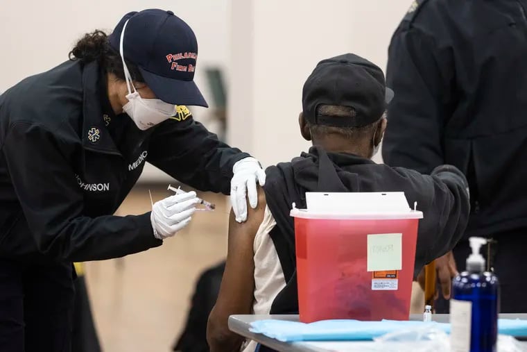 A Philadelphia Fire Department paramedic administers the Johnson & Johnson vaccine at a clinic in West Oak Lane on Monday.