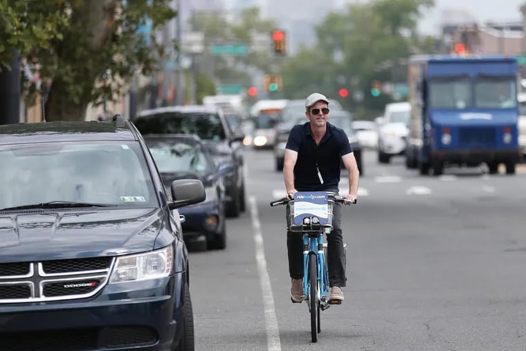 Inquirer columnist Mike Newall bicycles down South Broad Street in South Philadelphia as he follows a sightseeing route published in the Inquirer more than a century ago on Friday, July 27, 2018. TIM TAI / Staff Photographer
