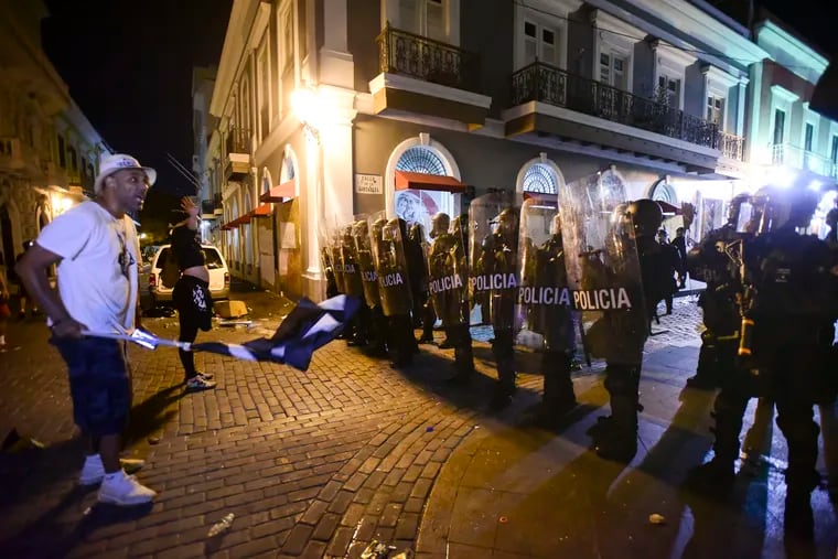 Demonstrators stand in front of riot control units during clashes in San Juan, Puerto Rico, Monday, July 22, 2019. Protesters are demanding Gov. Ricardo Rossello step down following the leak of an offensive, obscenity-laden online chat between him and his advisers that triggered the crisis.