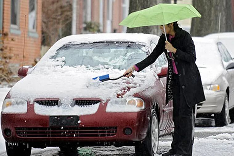 Scrapers and shovels might be needed Friday, according to forecasters. On Tuesday, Naureen Bhullar needed an umbrella to shield herself from chilly rain as she removed the snow from her car on West Second Street in Media. (Clem Murray / Staff Photographer)