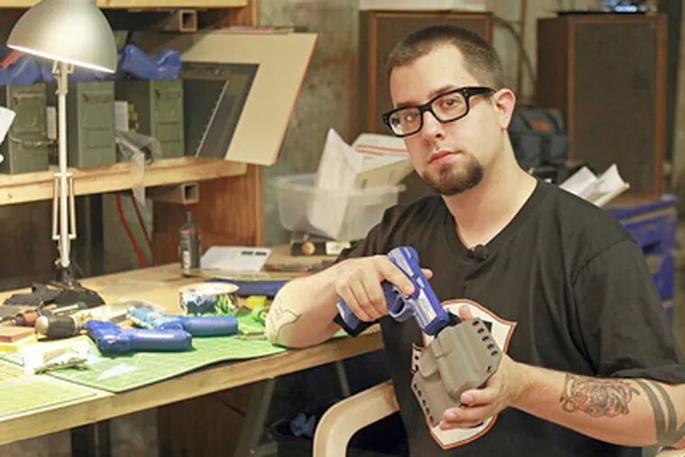Jon Hauptman, founder of PHLSTER, with one of the custom handgun holsters he manufactures in a basement workshop in lower Kensington. What started as a hobby has morphed into a niche business, with gross sales this year expected to reach $50,000. (AKIRA SUWA  /  Staff Photographer)