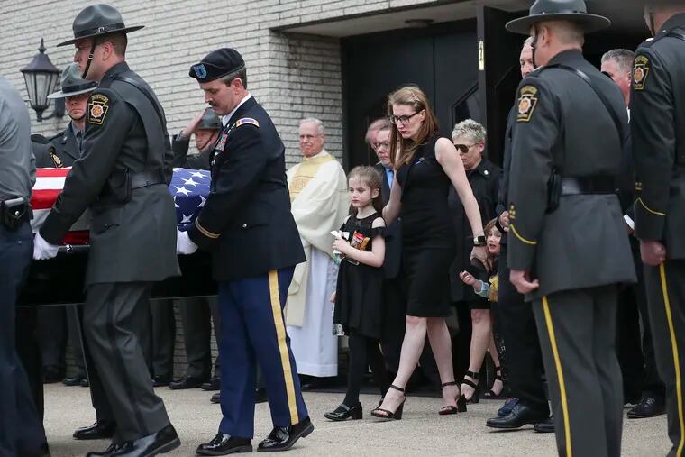 Stephanie Mack, wife of Trooper Martin Mack III, exits the Saint Michael the Archangel church behind her husband’s casket with her two daughters in Levittown, Pa. on Thursday. Mack, 33, was one of the two state troopers who was killed by a drunk driver on I-95 last week.