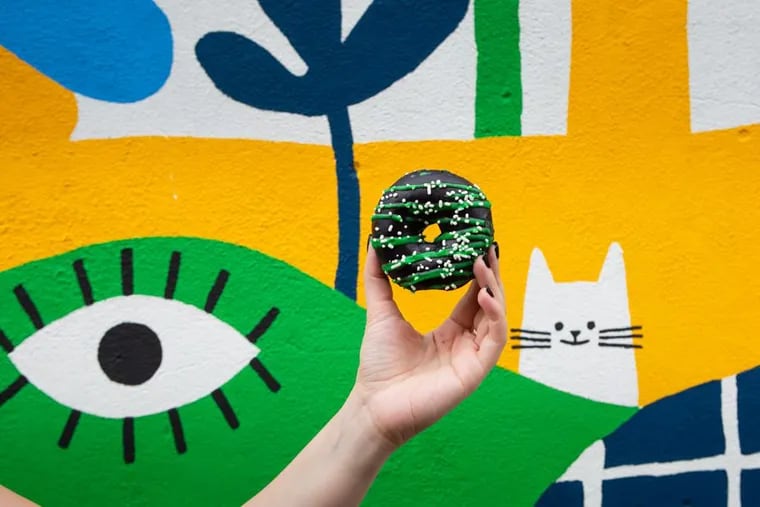 Mural Arts Philadelphia and Federal Donuts are teaming up to launch a Berries & Cream donut, pictured here in front of the Spring Arts District Mural by Lauren West.