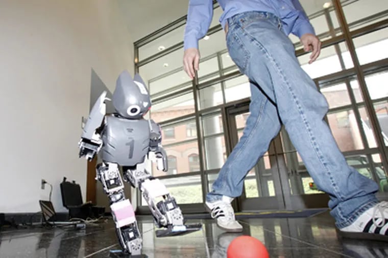 A humanoid soccer robot kicks a ball at the Philly Robotics Expo. Teams from Philly-area high schools joined in the event at Drexel University.  YONG KIM / Staff Photographer